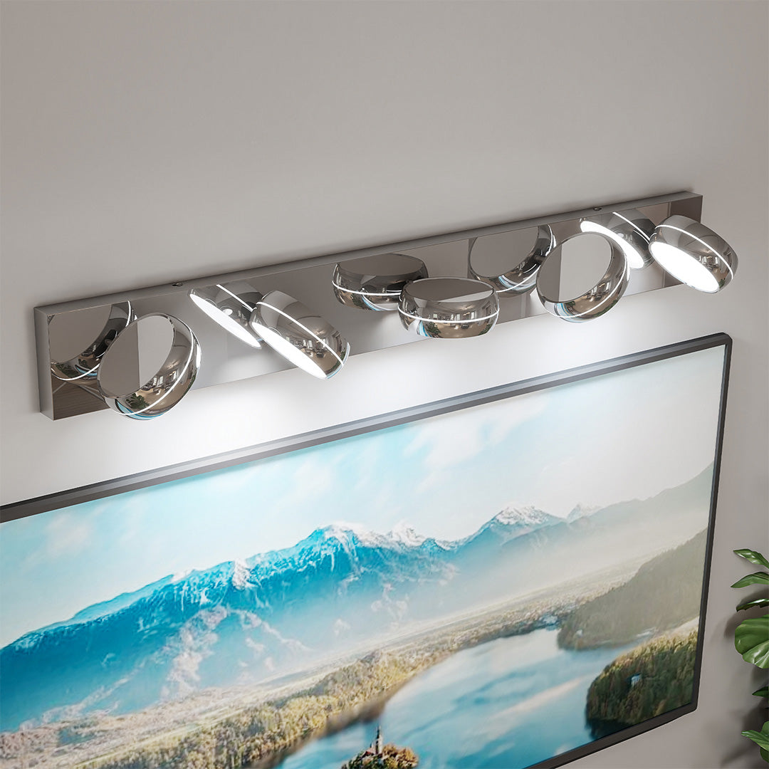 Modern chrome bathroom vanity light featuring glass shade chandelier design above ocean-themed decorative mirror art.