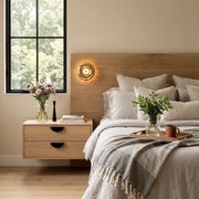 Modern chrome wall sconce mounted above a wood nightstand in a cozy bedroom setting.