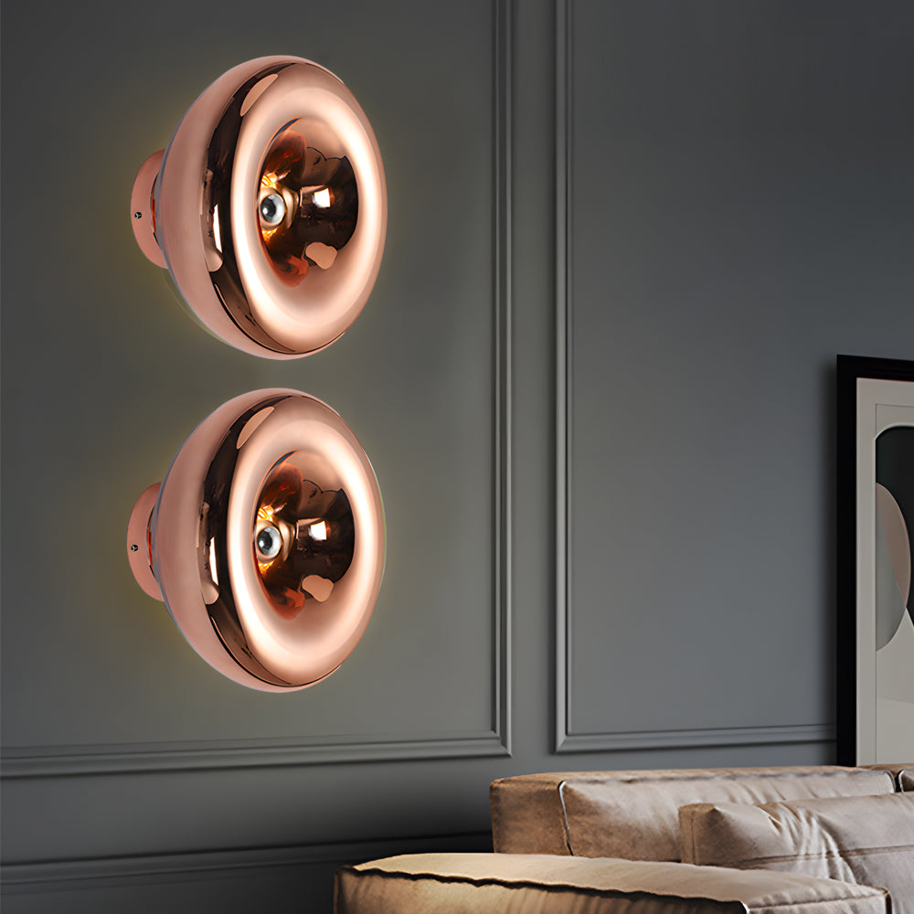 Modern chrome wall sconce with a golden interior, illuminating a cozy corner.