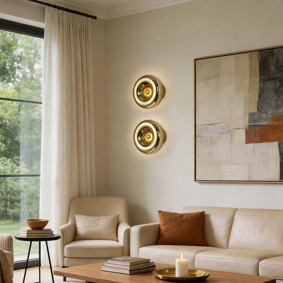 Modern chrome wall sconce with a round design, mounted in a cozy living room.