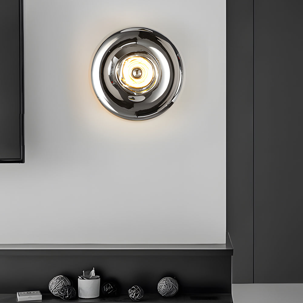 Modern chrome wall sconce with a sleek design, providing ambient lighting in a contemporary room.