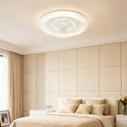Modern circular ceiling fan with light fixture installed in a large bedroom with a beige upholstered headboard and soft neutral decor. 