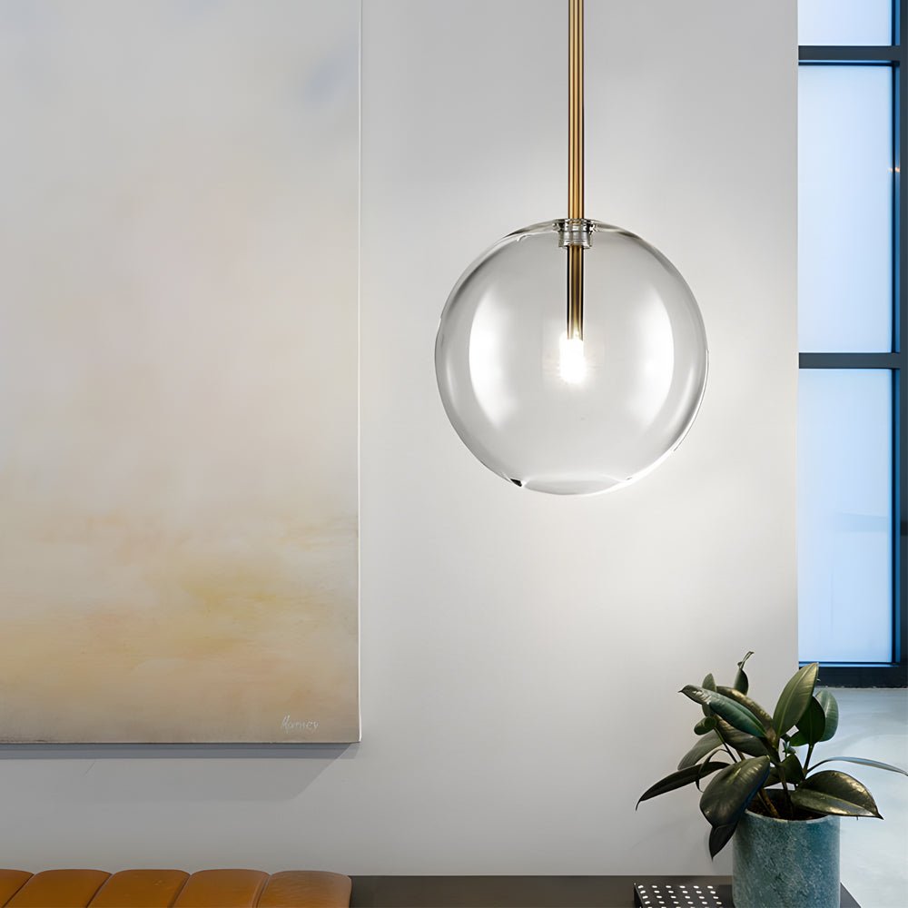 Modern clear glass globe pendant light hanging in a minimalistic dining room, enhancing the space with a warm glow.