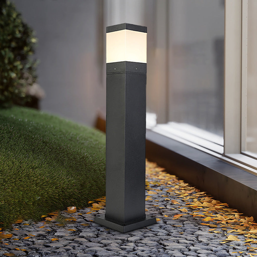 Modern commercial bollard lights with square design lighting up a grassy pathway and stepping stones.