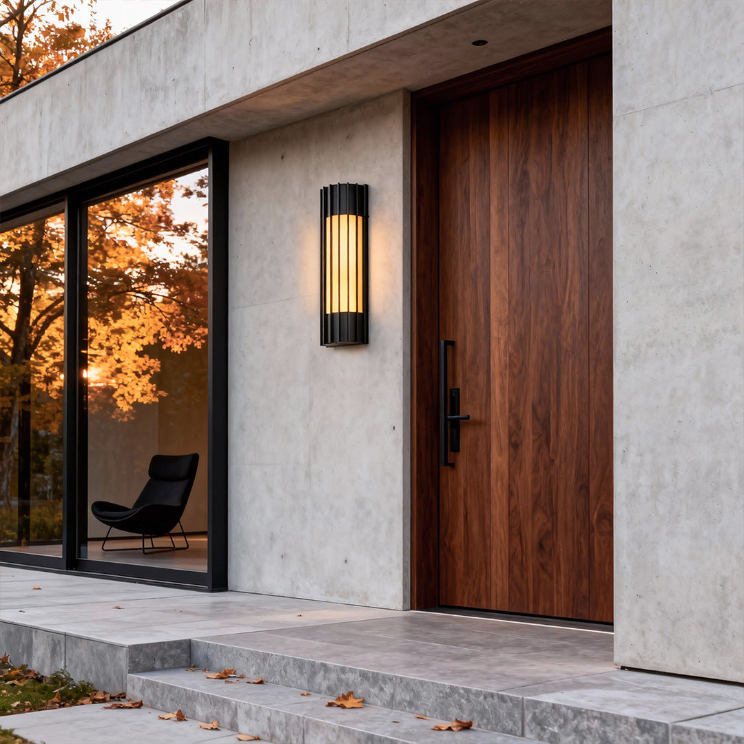 Modern copper outdoor wall lights installed beside a wooden door, providing sleek and warm entrance illumination.