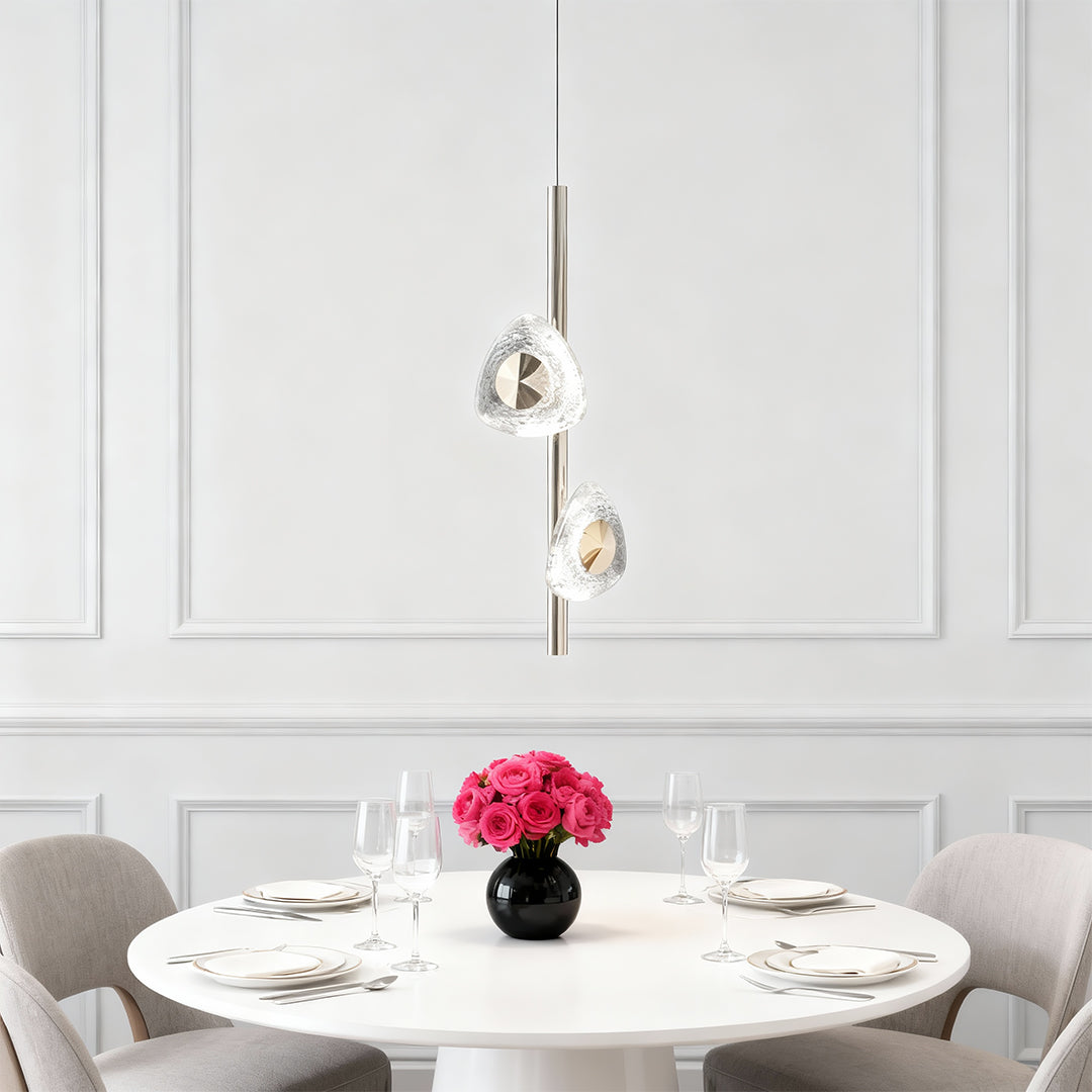 Modern crystal pendant light suspended above white round dining table with elegant chairs and floral centerpiece