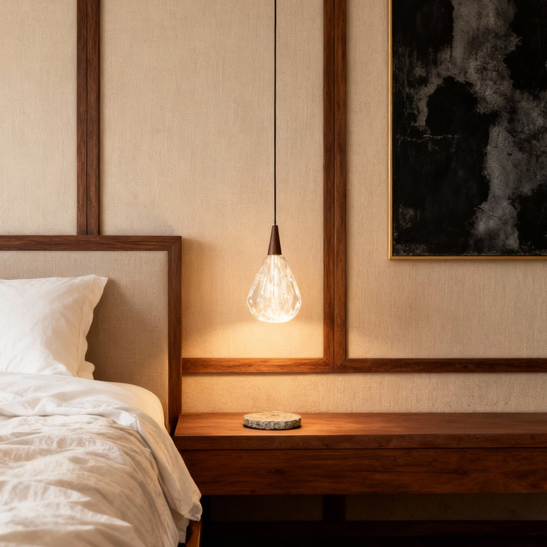 Modern crystal pendant lighting casting warm glow in minimalist bedroom corner with rich wood furniture and monochromatic palette