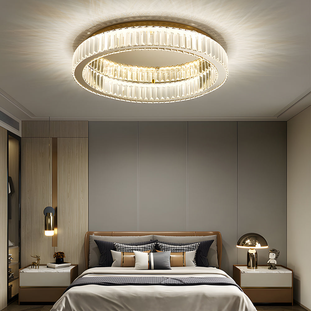 Modern crystal ring ceiling light centered above a stylish bed.