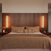 Modern crystal wall lights mounted above a bed against a warm wood accent wall.
