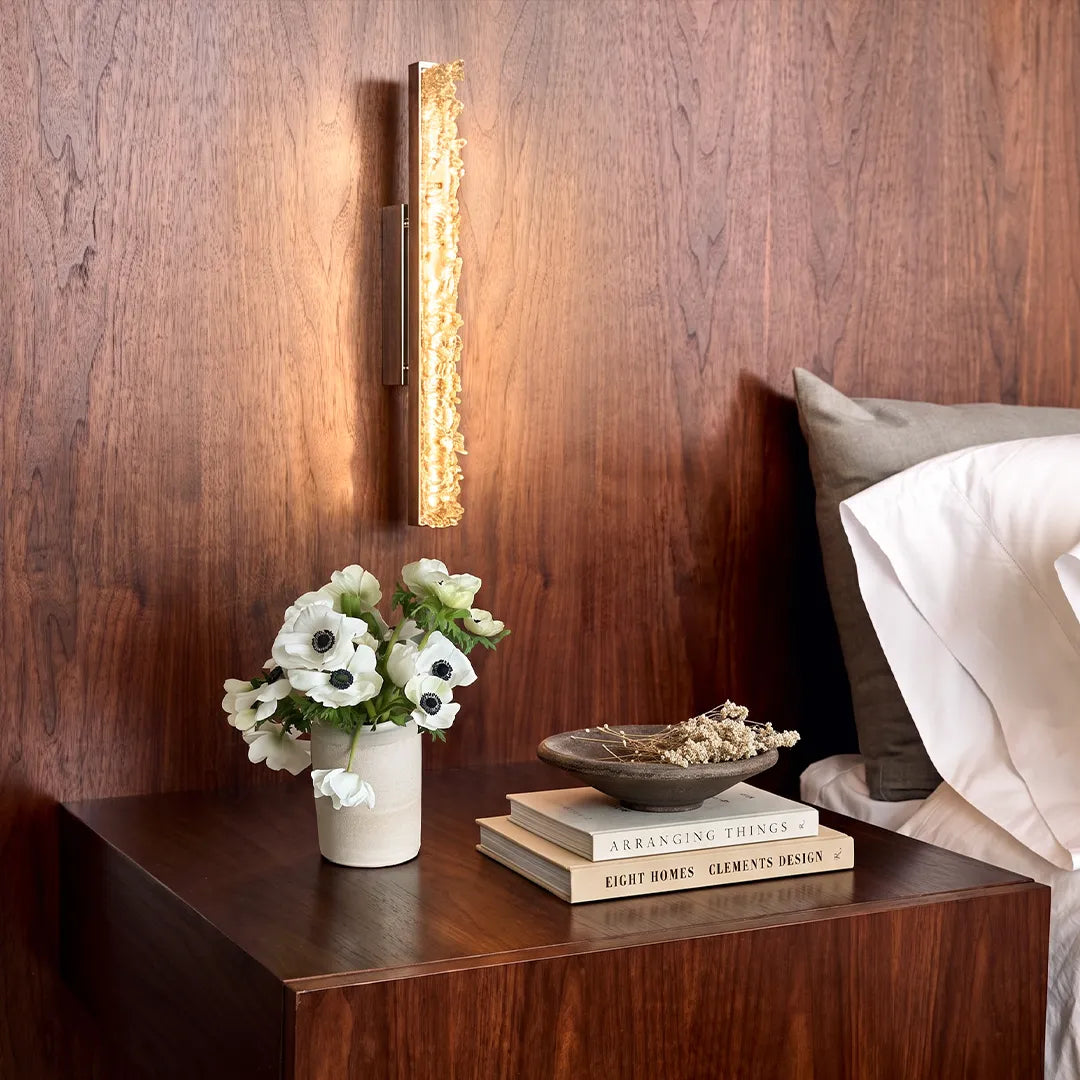 Modern crystal wall lights adding warm bedside illumination beside a dark wood headboard wall.