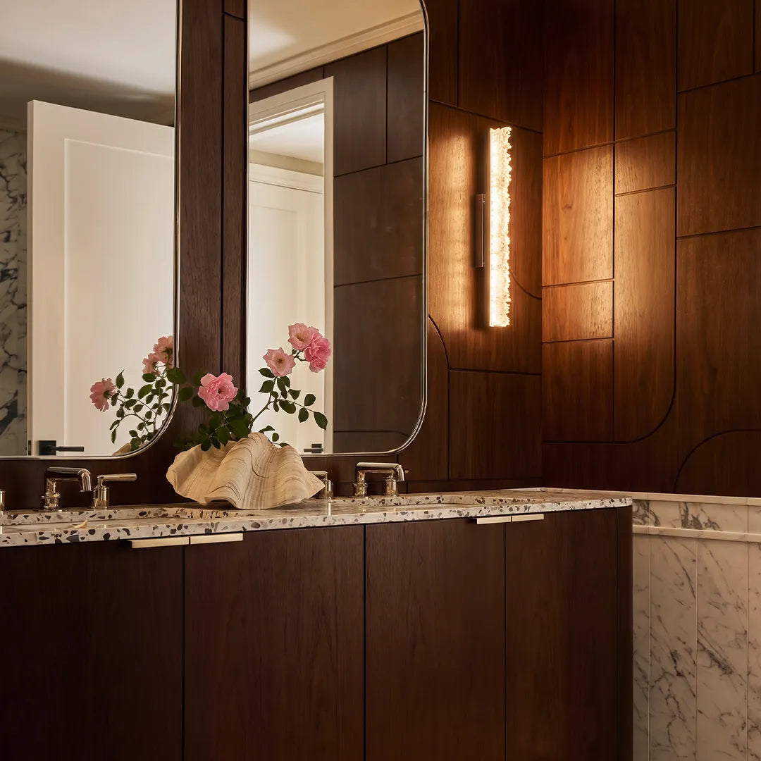 Modern crystal wall lights flanking a bathroom mirror above a dark wood double vanity.