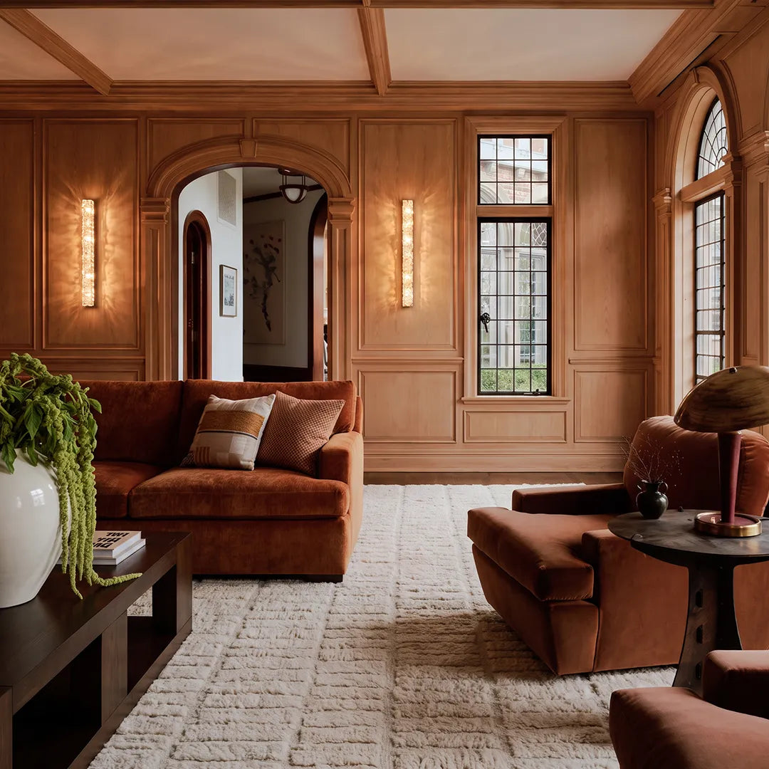 Modern crystal wall lights installed in a warm paneled living room with arched windows and seating.