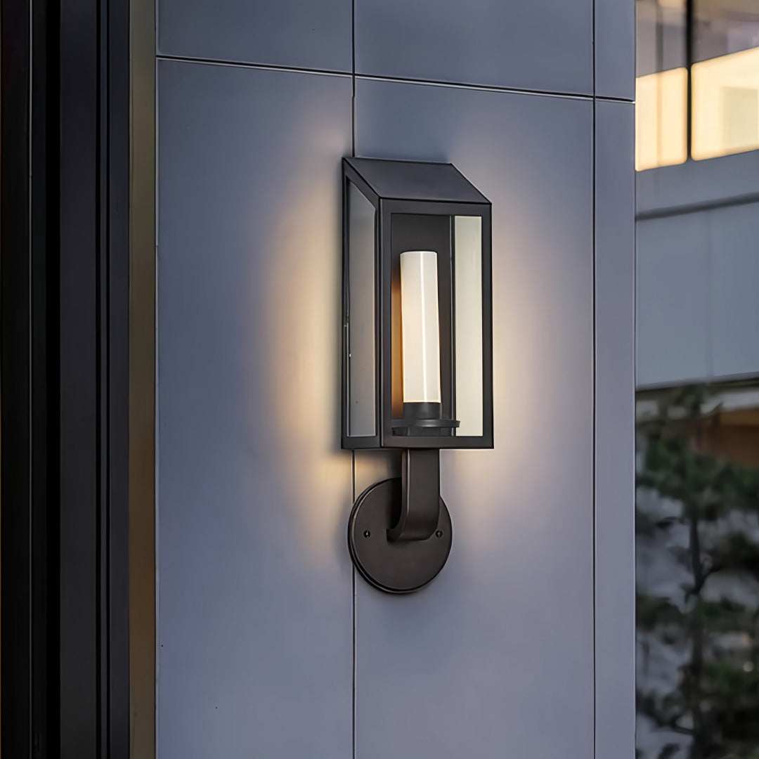 Modern outdoor wall mount light fixture installed beside a doorway, creating soft ambient evening lighting.