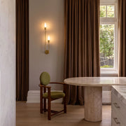 Modern double heads wall sconce in a warm neutral dining corner, featuring two slim vertical lights with a gold wall mount.