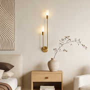 Modern double heads wall sconce with a gold finish, providing elegant illumination in a minimalist bedroom.