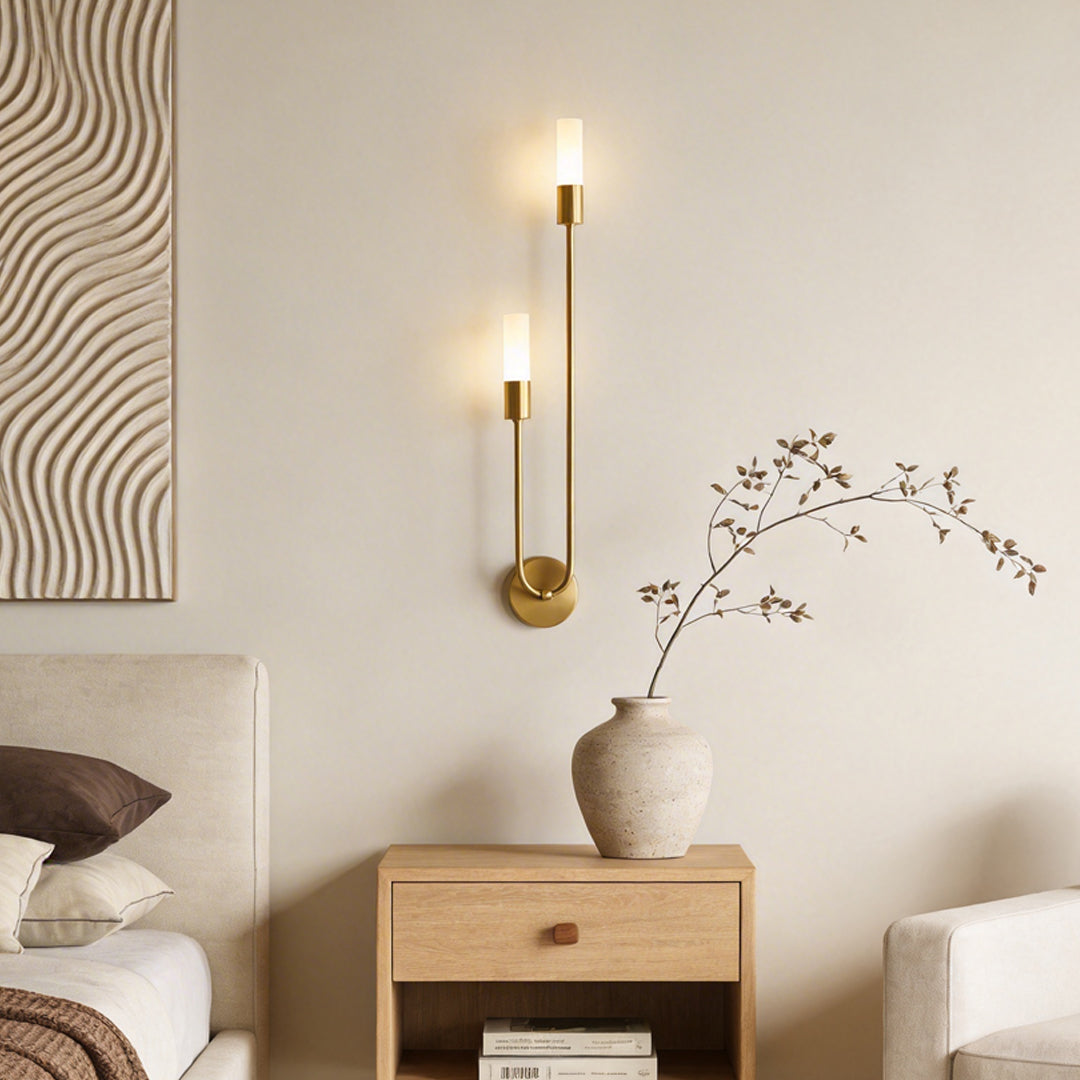 Modern double heads wall sconce with a gold finish, providing elegant illumination in a minimalist bedroom.