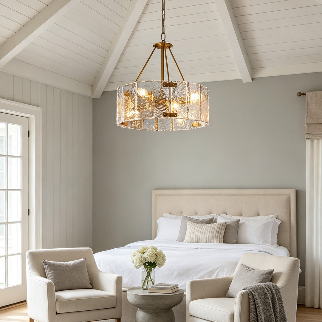 Modern drum chandelier hanging above a serene bedroom with vaulted ceiling and soft neutral decor.