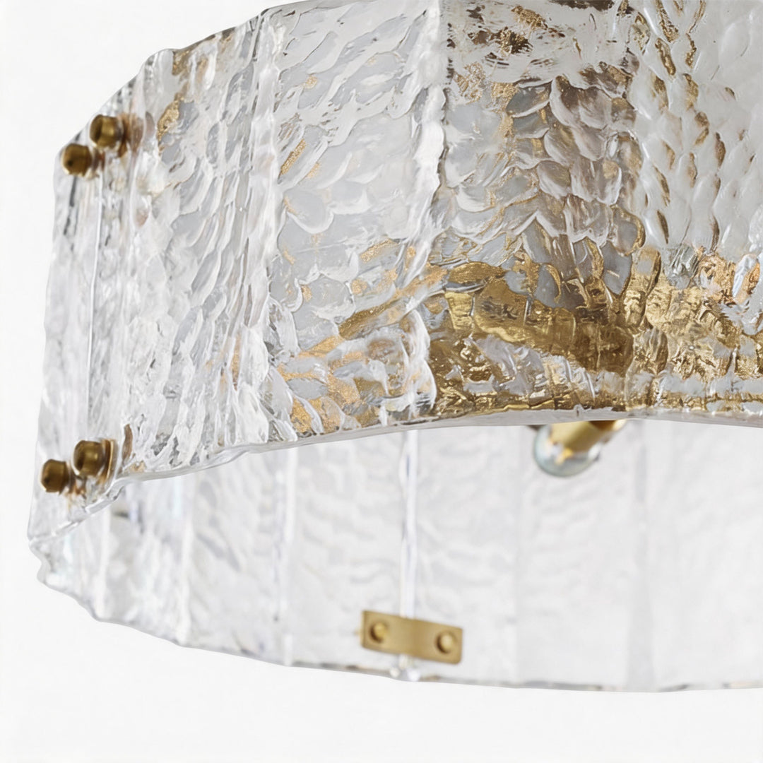 Modern drum chandelier detail featuring hammered glass texture and gold metal trim accents.