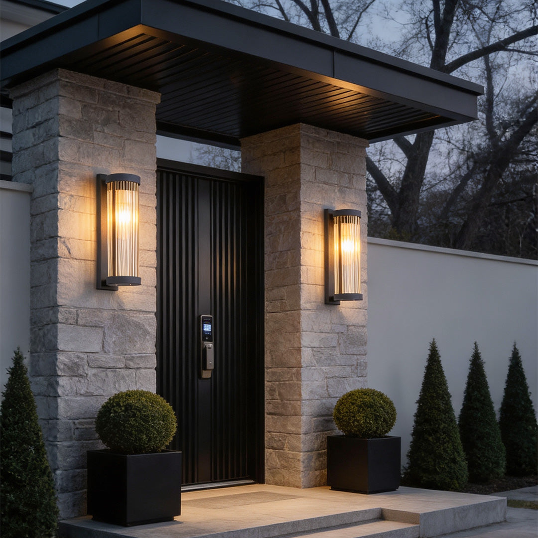 Modern front entryway featuring stone pillars illuminated by vertical outdoor wall mount lights with textured glass.