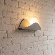 Modern exterior wall lighting with a sculptural LED design mounted on a textured brick wall.