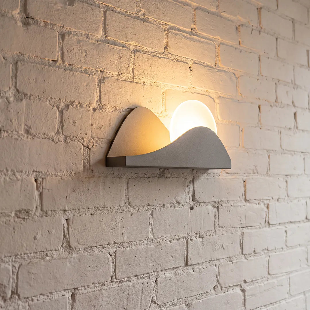 Modern exterior wall lighting with a sculptural LED design mounted on a textured brick wall.