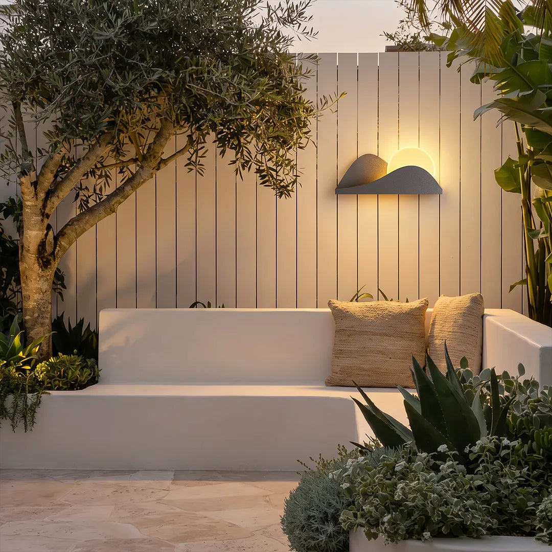 Modern exterior wall lighting casting a warm glow above contemporary outdoor patio seating.