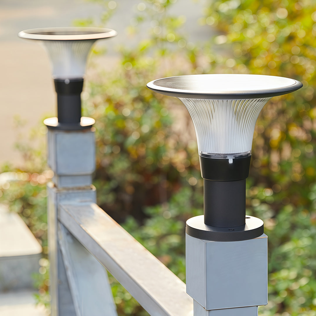 Modern fence post cap lights fixture with a textured diffuser, installed on a grey metal railing post.