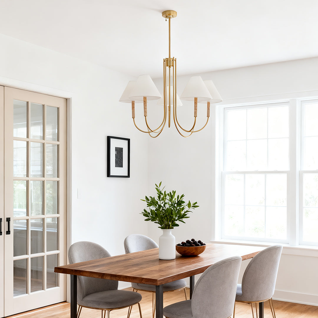 Modern four-light cloth shade chandelier illuminating a rustic wood dining table near large French doors.
