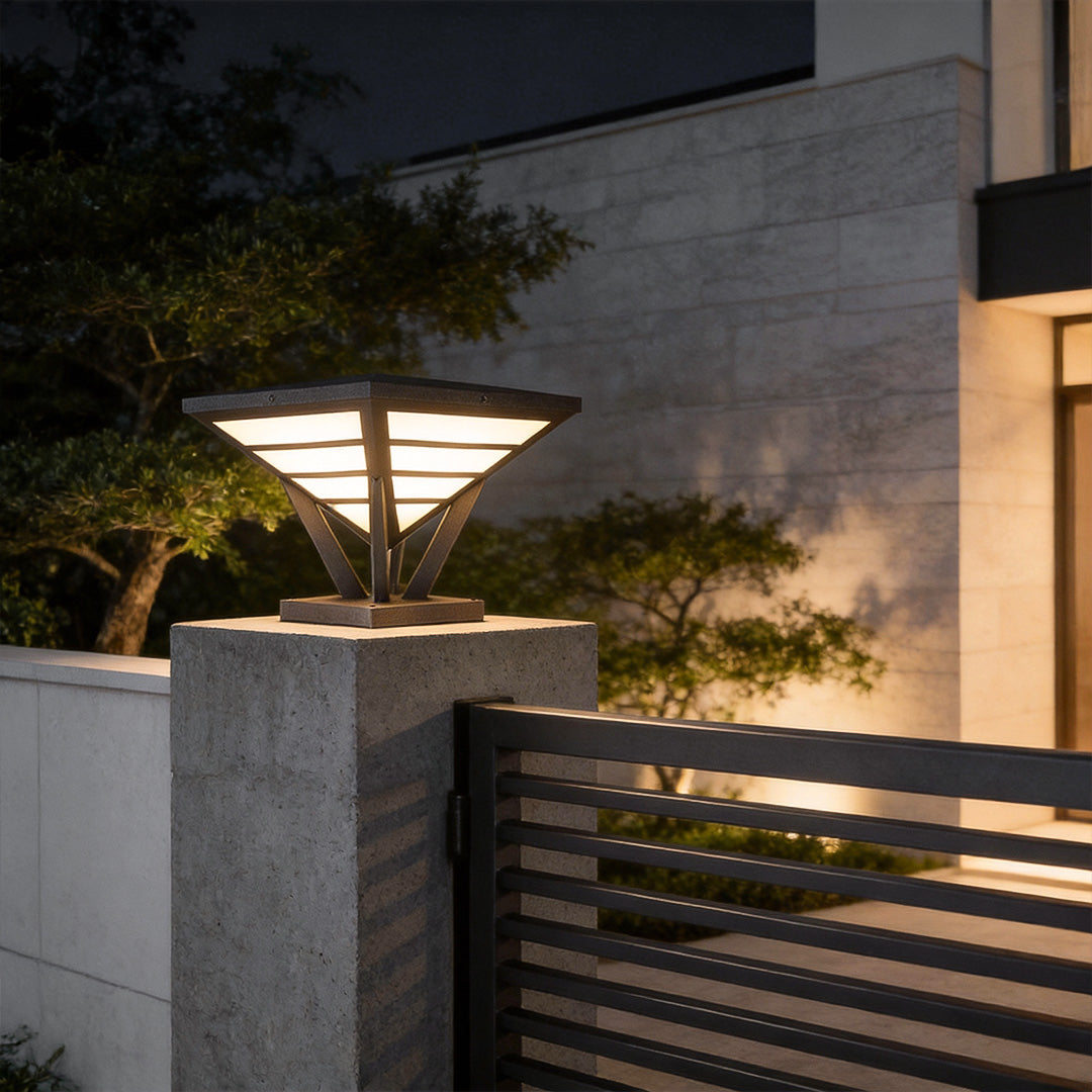 Modern gate pillar light installed on a concrete pillar near a metal gate.