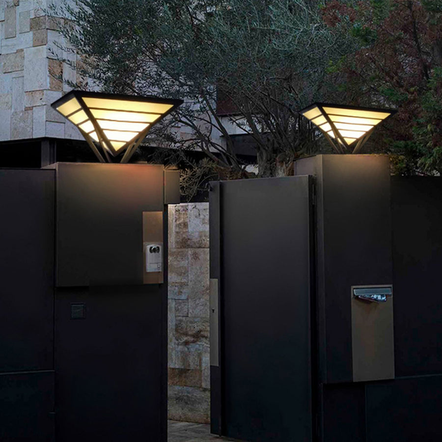 Modern gate pillar lights mounted on exterior fence columns at night.