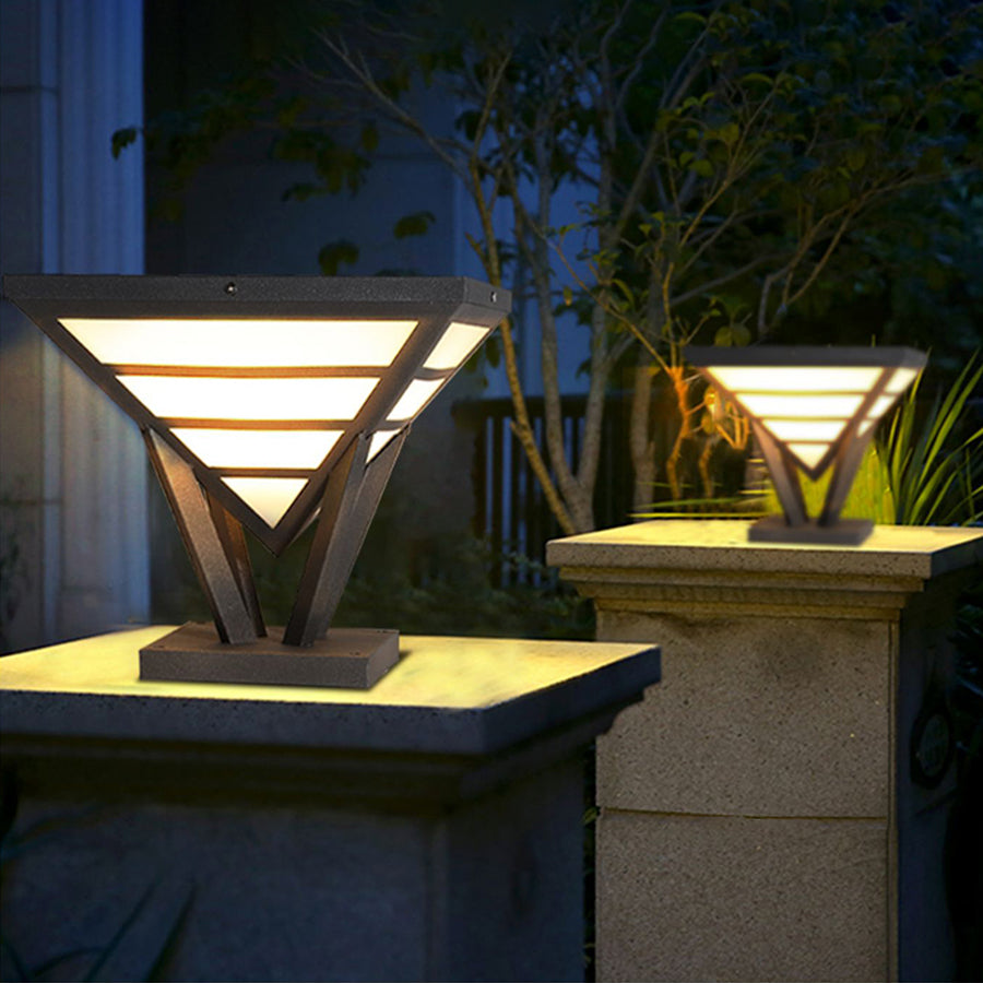Modern gate pillar lights installed on stone columns in a landscaped yard.