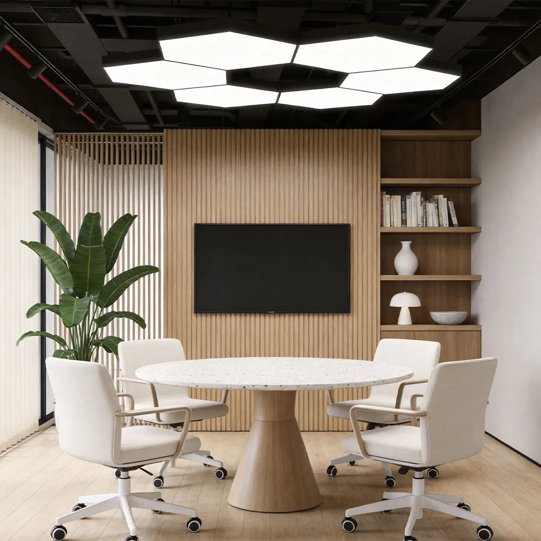 Modern geometric chandelier suspended above a round conference table in a contemporary meeting room.