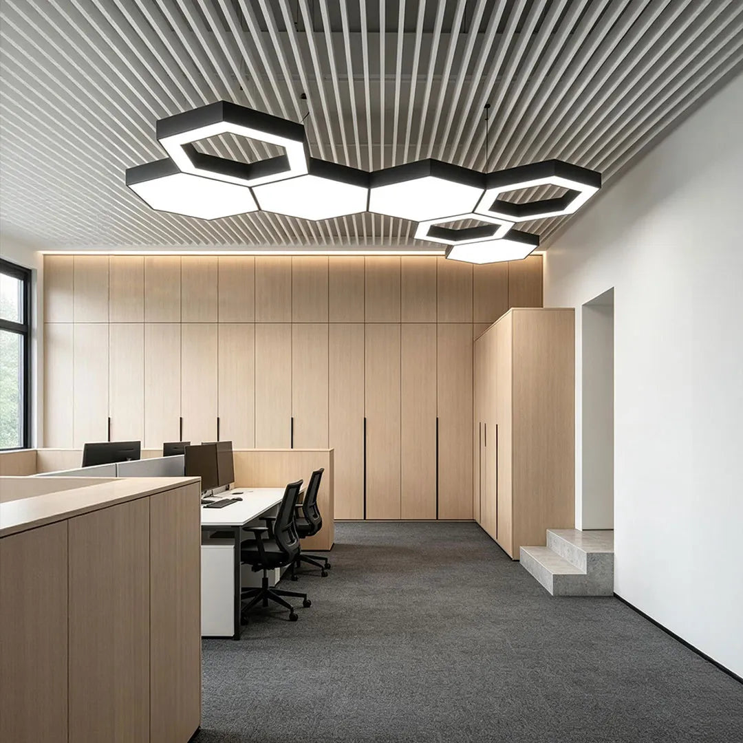 Modern geometric chandelier installed in an open office with workstations and wood-paneled walls.