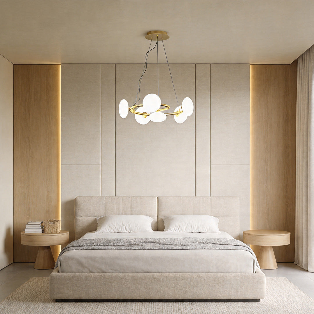 Modern glam chandelier centered above a bed in a minimalist bedroom with soft beige tones and clean lines.