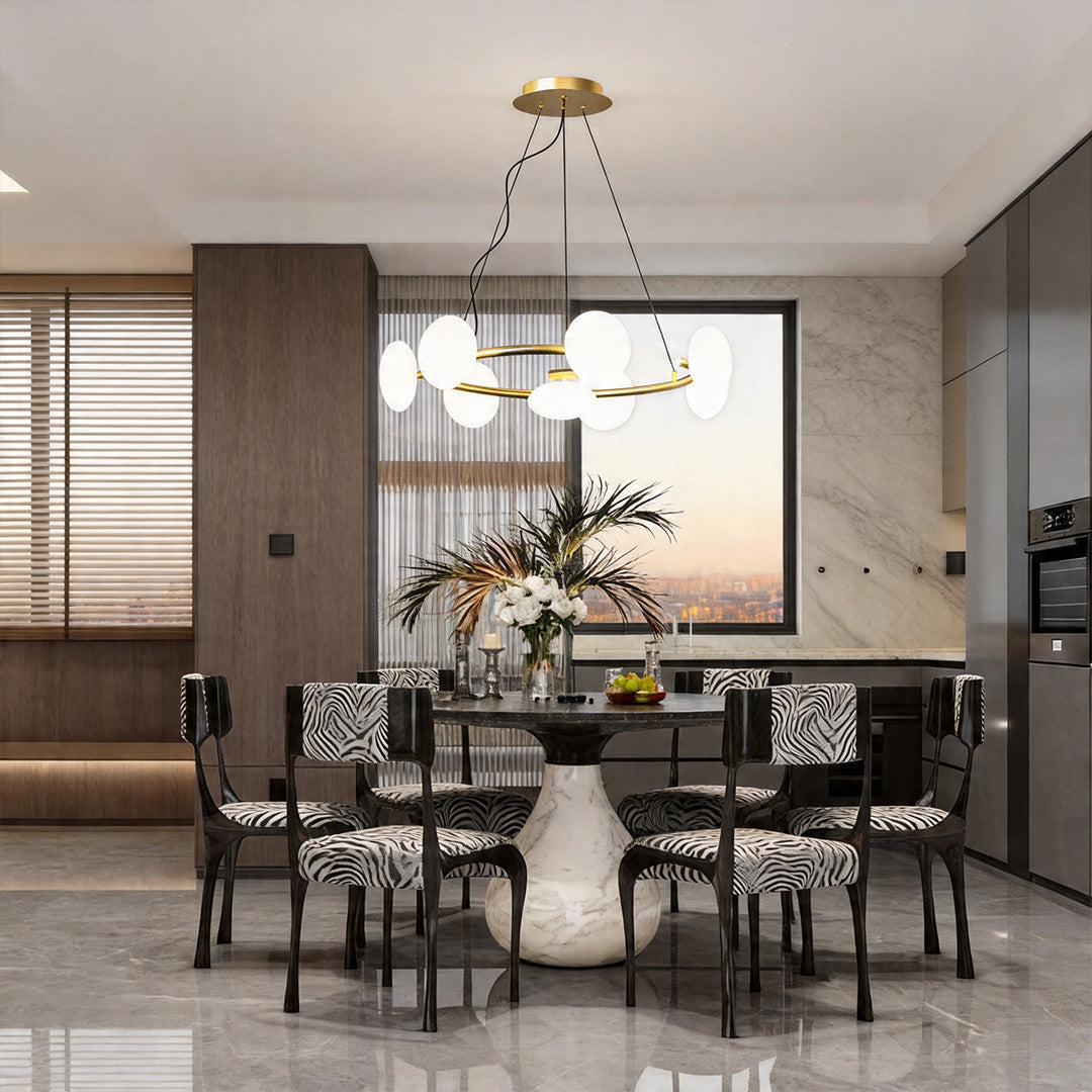 Modern glam chandelier illuminating a dining area with large windows and stylish interior design elements.