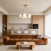 Modern glam chandelier hanging in a contemporary living room with warm ambient lighting and elegant neutral decor.