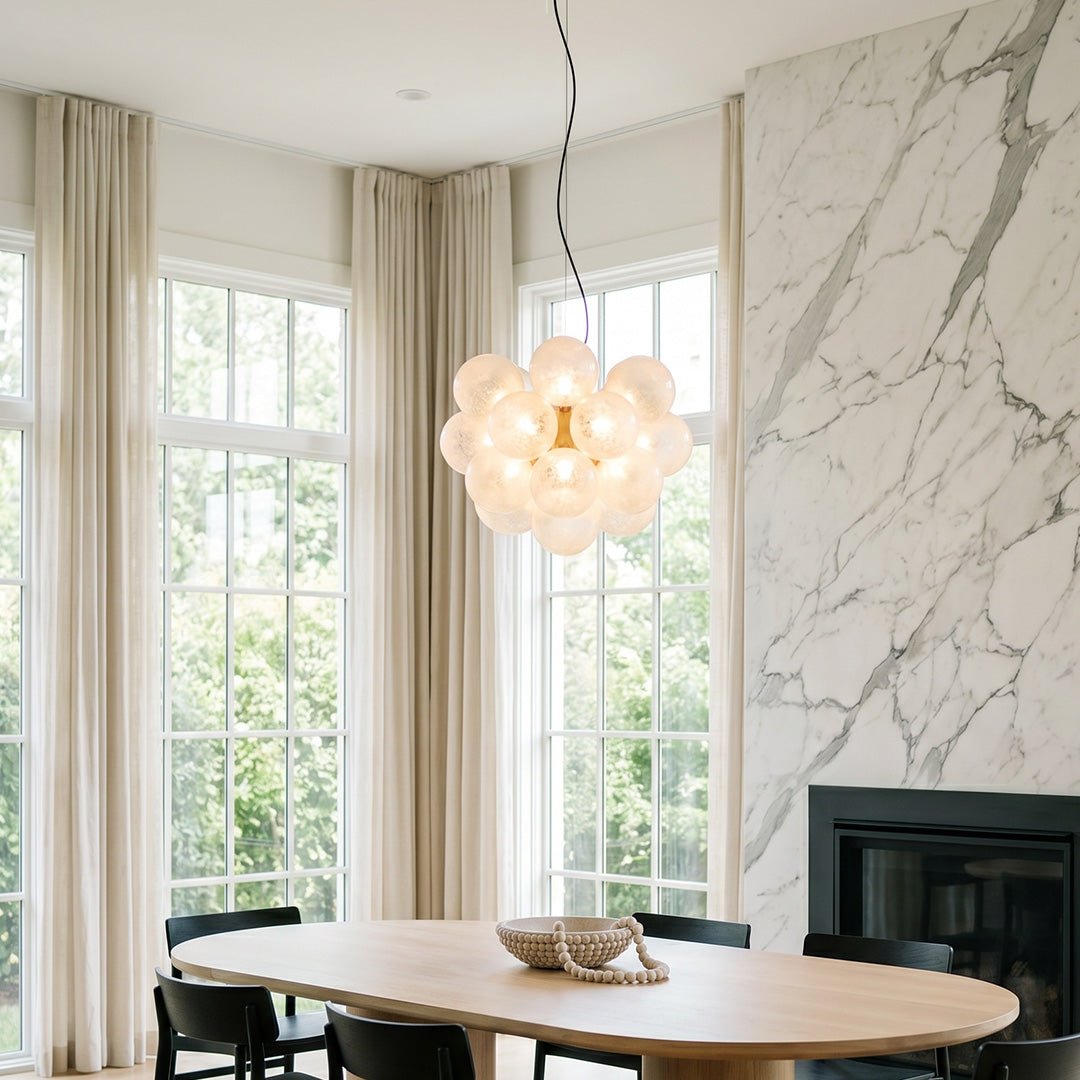 Modern glass bubble chandelier hanging in bright living room with marble wall background.