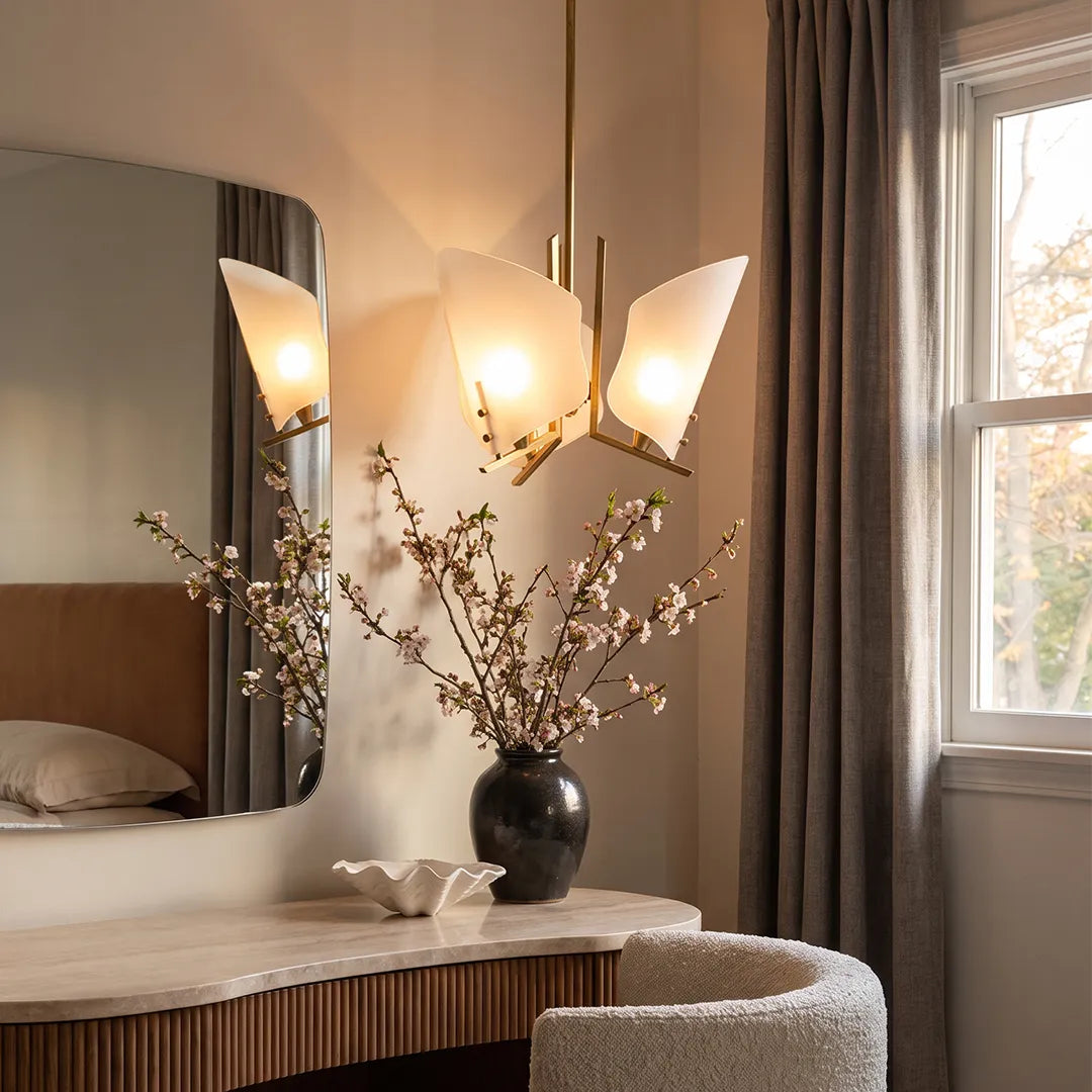 Modern glass chandelier placed near a vanity in a bright bedroom with a window and decorative vase.