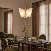 Modern glass chandelier hanging above a dining table in a warm contemporary dining room.