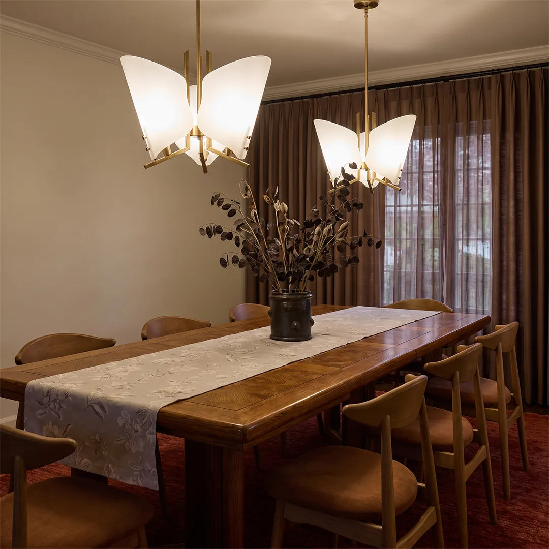 Modern glass chandelier suspended above a long dining table in an elegant dining space.