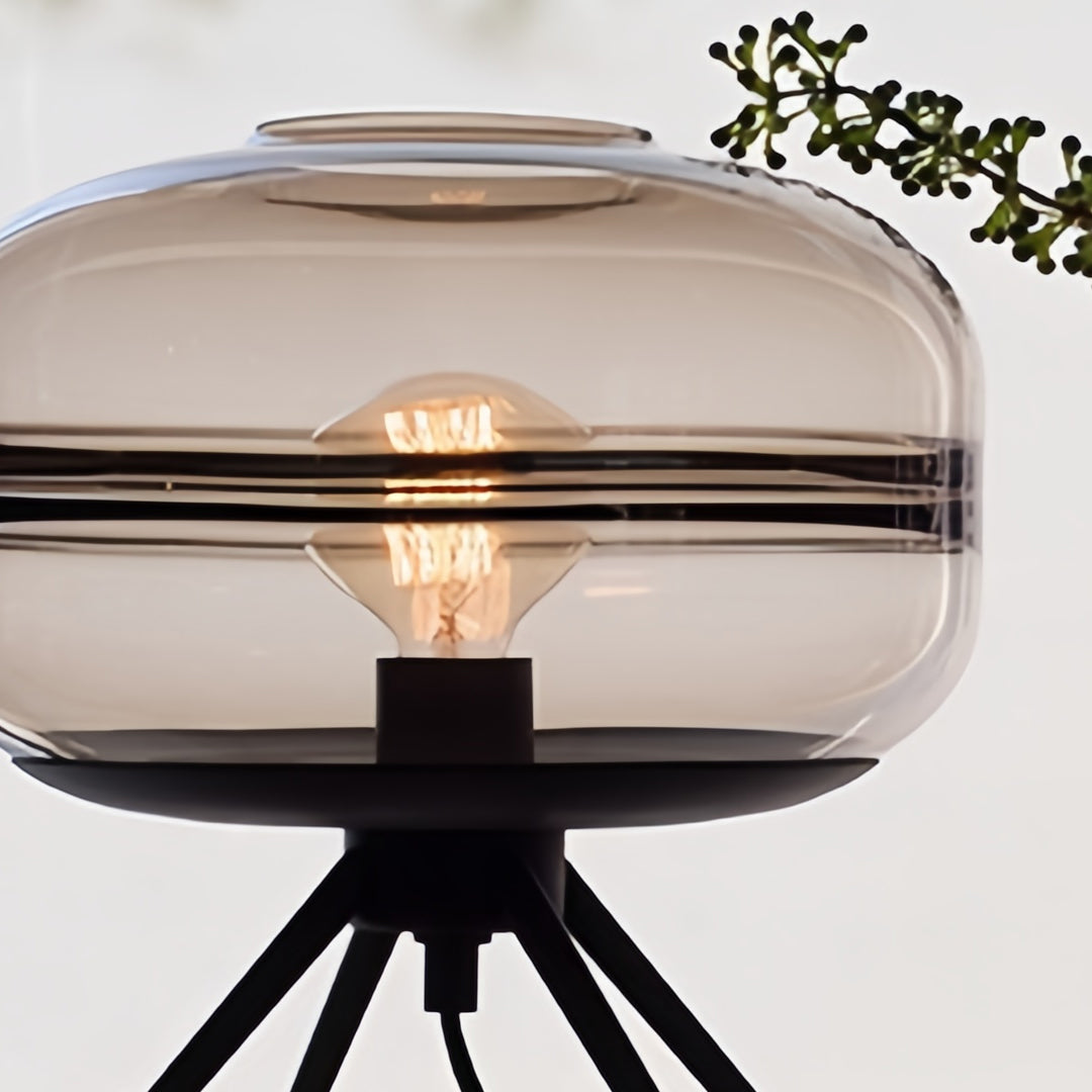 Modern glass small table lamp with clear shade creating bright accent lighting beside decorative elements