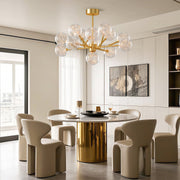Modern glass globe chandelier creating focal point in elegant dining space with brass table