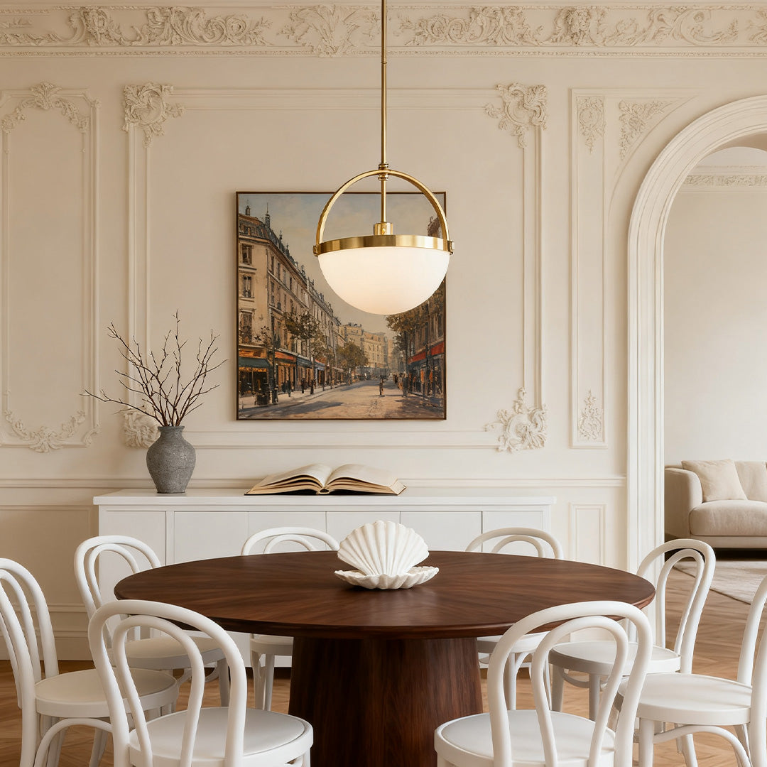 Modern globe gold and white pendant light centered over a round wood dining table in a contemporary formal room with ornate molding.