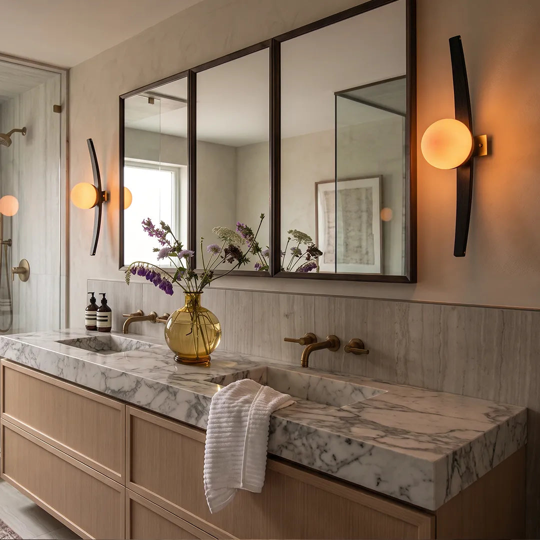 Modern globe wall sconce pair mounted beside a bathroom vanity mirror with warm accent lighting.