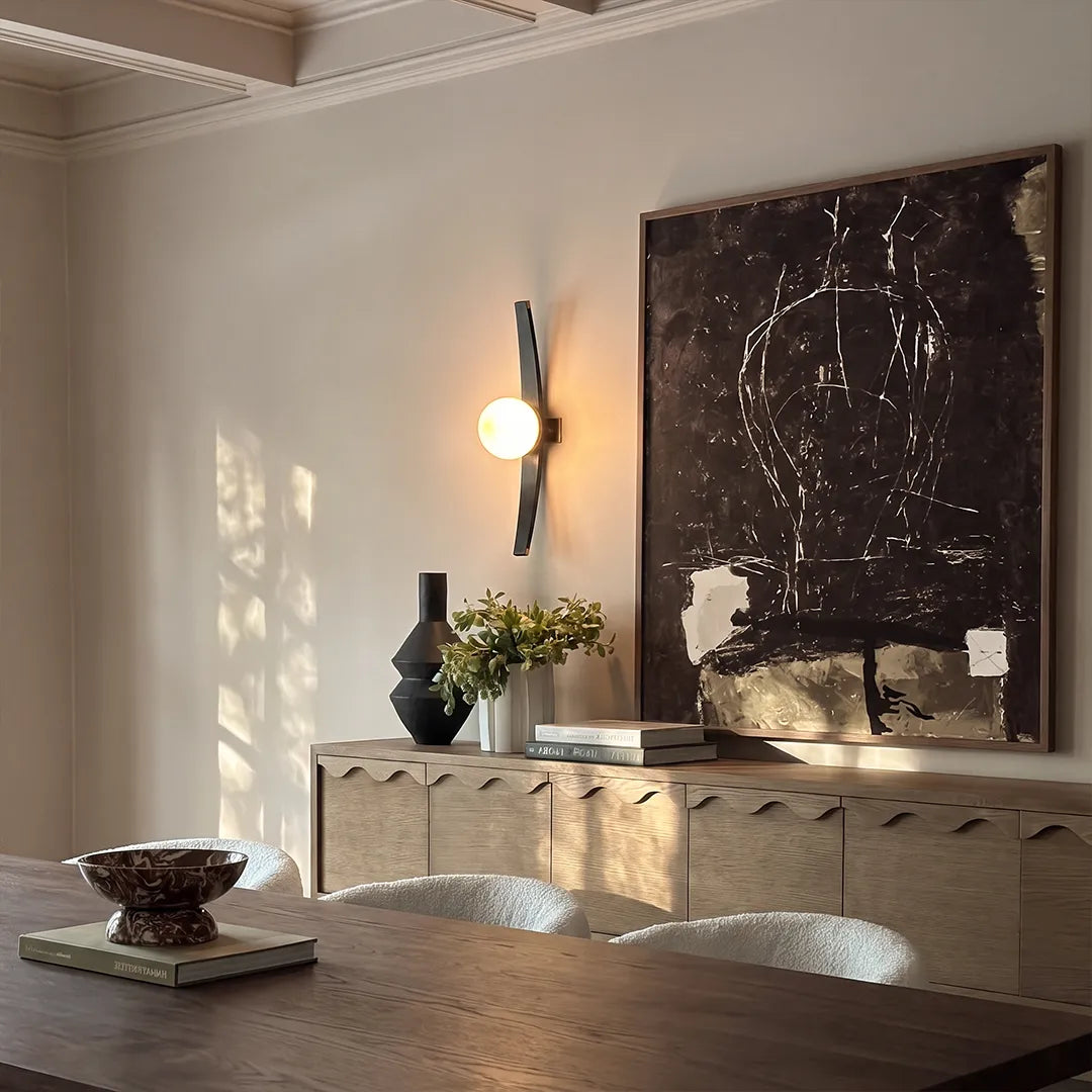 Modern globe wall sconce illuminating a living room wall above a console with warm ambient lighting.