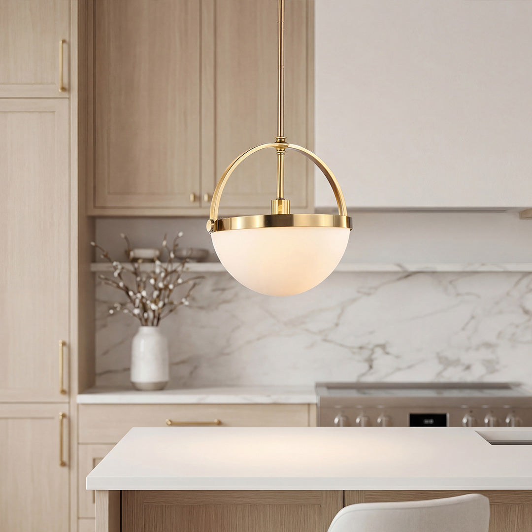 Modern gold and white pendant light with a brass arch and frosted bowl over a kitchen island.