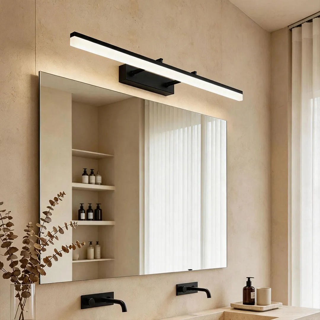 Modern gold bathroom vanity light bar above a framed mirror in a beige bathroom interior.