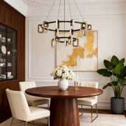 Modern gold chandeliers providing focal lighting in dining room with round wood table and vibrant colorful wall art