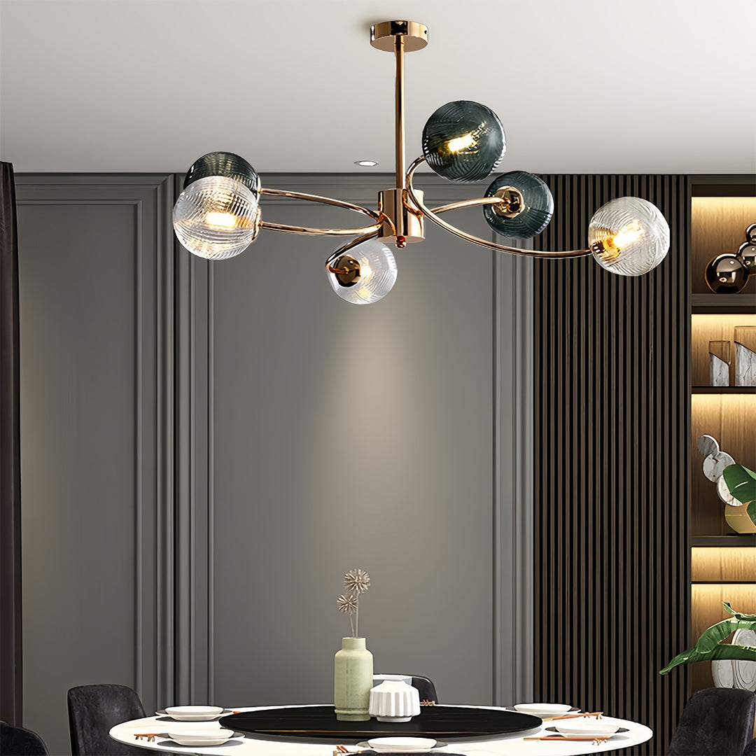 Modern gold and clear glass flush mount ceiling light fixture over a minimalist white dining table in a dark-paneled room.