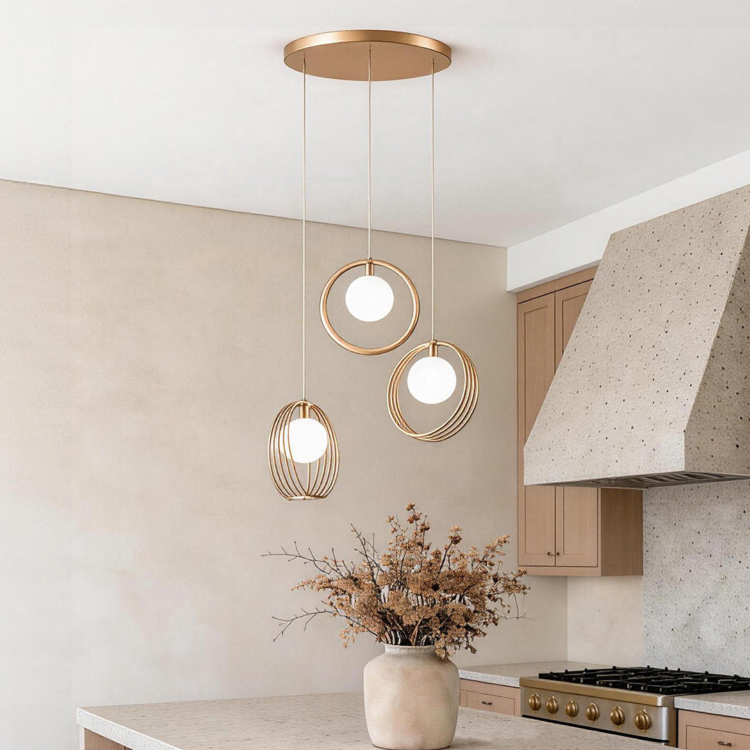Modern 3 bulb pendant light with gold geometric rings and frosted globes in a warm kitchen.